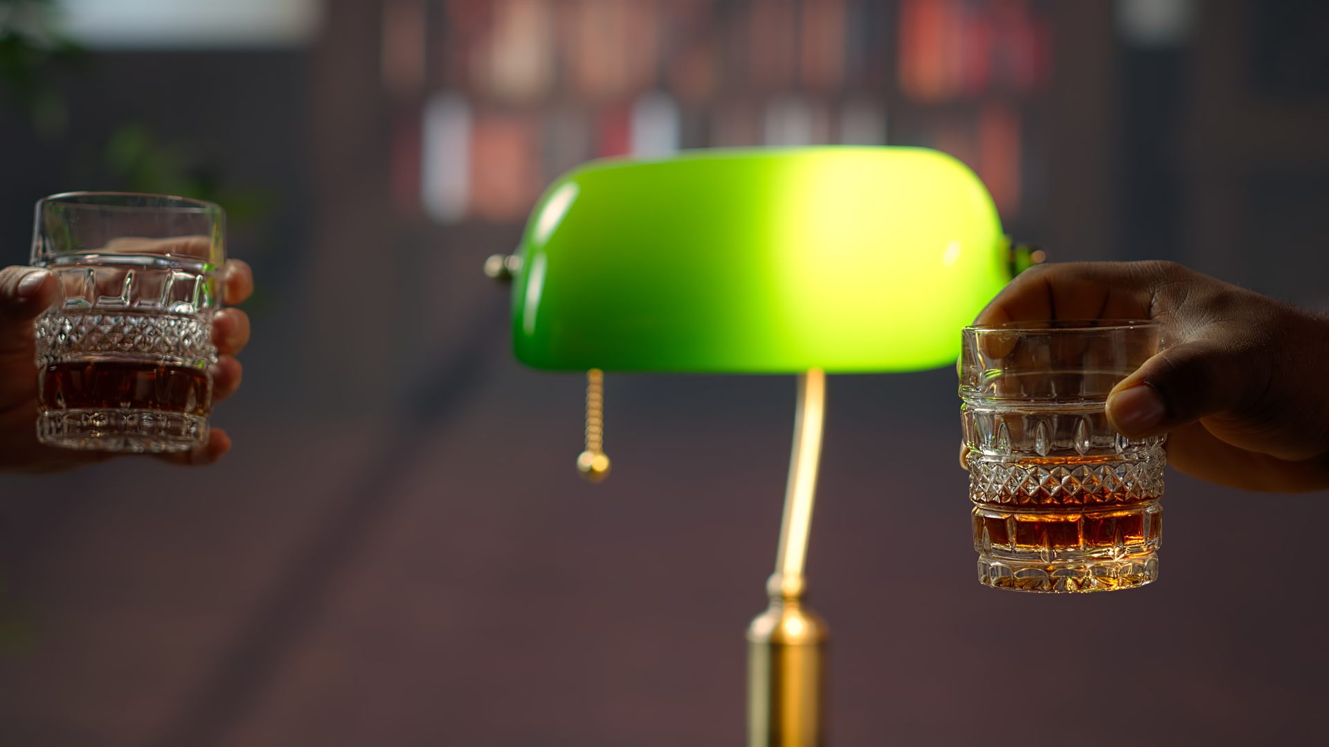 Biblioteca classica con lampada verde, scaffali di legno e due bicchieri da whisky